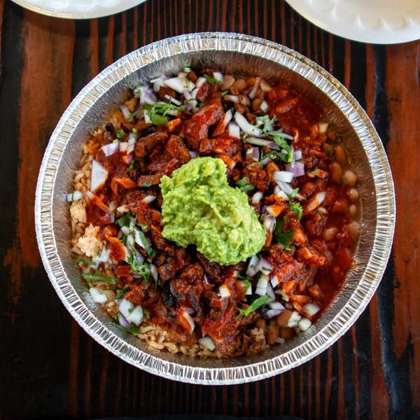 Tacos Chapala's Mexican food bowl with rice, beans, meat, onions, cilantro, and guacamole.