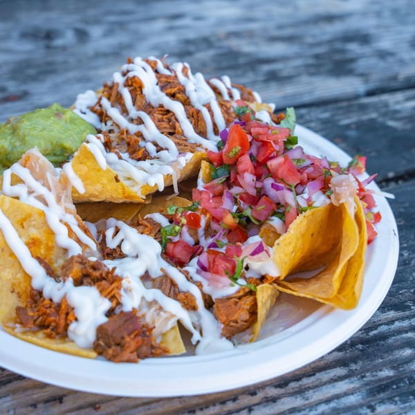 A plate of Tacos Chapala nachos with shredded meat, pico de gallo, guacamole, and crema.