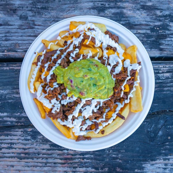 Carne asada fries from Tacos Chapala, topped with guacamole, sour cream, and cheese.