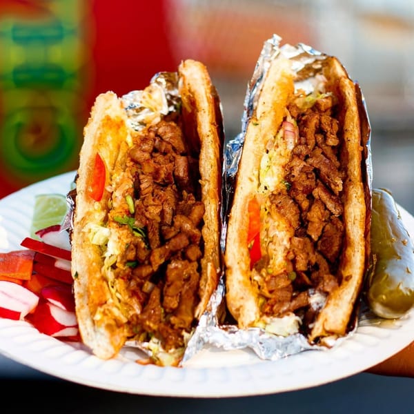 Two Tacos Chapala Mexican tortas, filled with meat, lettuce, and tomato, served with radishes and a pickle.
