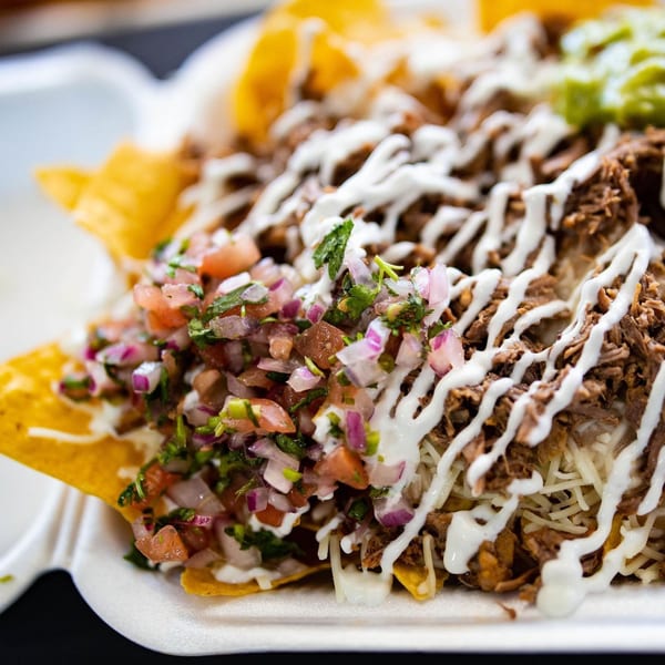 Close-up of Tacos Chapala's loaded nachos with shredded meat, pico de gallo, sour cream, and guacamole.