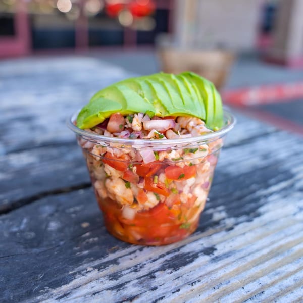 Tacos Chapala's fresh ceviche with shrimp, tomatoes, onions, and avocado in a clear cup on a wooden table.